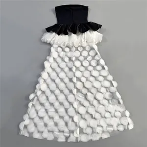 Detail of strapless bandeau dress with black top and white tiered tulle skirt.