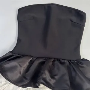 Close-up detail of black strapless bandage dress with satin peplum and white tulle skirt