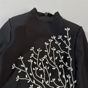 Close-up of intricate silver rhinestone vine embellishment on a black bandage dress.
