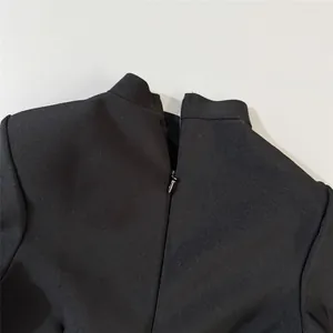 Close-up of the back zipper and high collar detail on a black bandage slimming dress