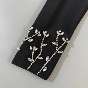 Close-up detail of black bandage dress sleeve featuring elegant crystal branch embroidery
