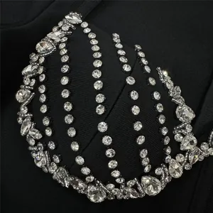 Detailed macro view of heavy rhinestone embellishments on a black bandage dress bodice