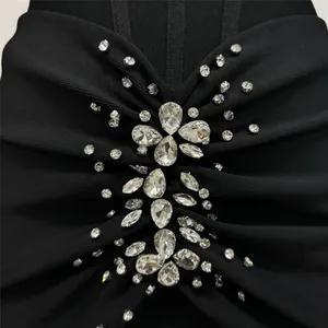 Detailed macro view showing sparkling rhinestone embellishments on a black bandage dress