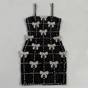 Close-up of black bandage dress featuring intricate pearl grid and rhinestone bows