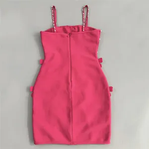 Detail view of a bright fuchsia bandage mini dress with pearl straps and side bows.