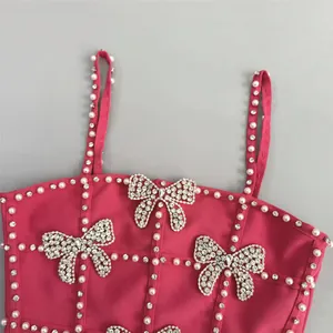 Detailed view of a pink bandage dress featuring pearl and rhinestone bow motifs.