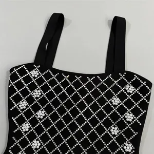Close-up detail of rhinestone lattice and pearl floral patterns on a black bandage dress