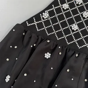 Close-up of black evening dress with rhinestone grid and pearl flower embellishments