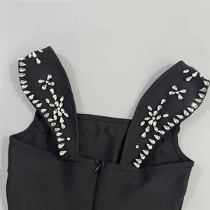 Detail van zwarte bandagejurk met glinsterende strass-bloempatroon op bandjes