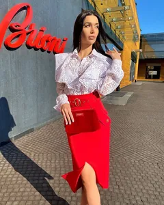 Detail showing a woman in a white floral lace top and high-waisted red skirt with a slit.