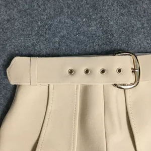 Close-up detail of high-waist beige bandage dress featuring a belt with gold buckle