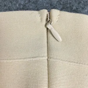 Detailed close-up showing the invisible zipper and ribbed fabric of a beige bandage dress