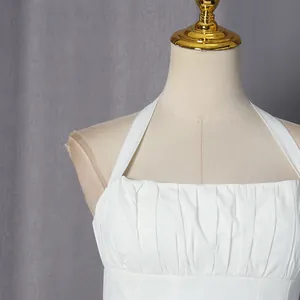 Gedetailleerde close-up van een witte halterjurk met verfijnd geplooid detail op de borst