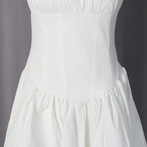 Detailopname van de strakke taille en plooirok van een witte jurk in Franse stijl.