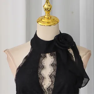 Detailed view of black lace halter neck evening dress with elegant 3D floral accent