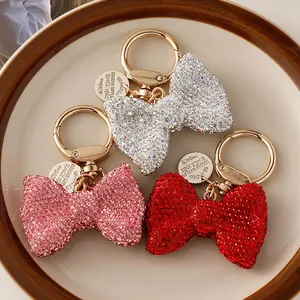 Detailed view of three sparkling rhinestone bow keychains in silver, pink, and red colors.