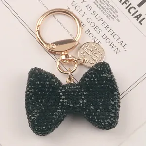 Close-up of black rhinestone bow keychain with elegant gold hardware and tag.
