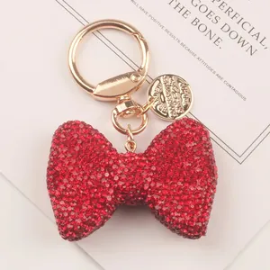 Macro view of a luxury red rhinestone bow keychain with elegant golden clasp and charm