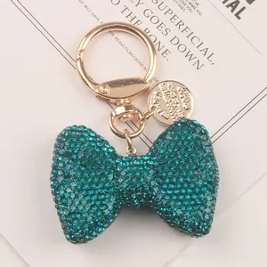 Detailed close-up of a sparkling teal rhinestone bow keychain with elegant gold hardware.
