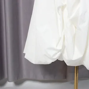 Detailopname van de witte ruches op een elegante avondjurk in een verfijnde Franse stijl