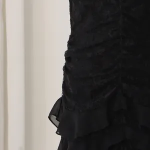 Close-up detail of black lace fabric and ruffled hem on a mermaid evening dress.