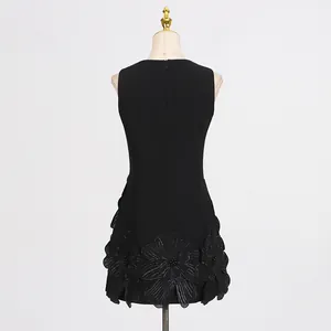 Rear view detail of black sleeveless dress featuring delicate 3D floral hem appliqués