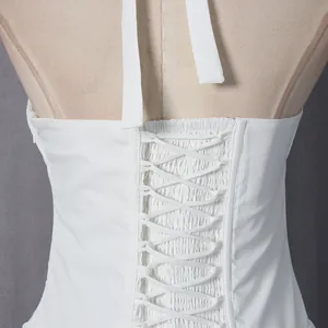 Gedetailleerd achteraanzicht van een witte halterjurk met vetersluiting en gesmokte stof detail.