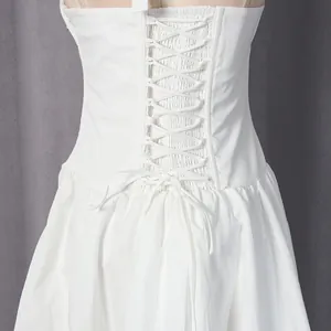 Detail van een witte Franse jurk met vetersluiting aan de achterkant.