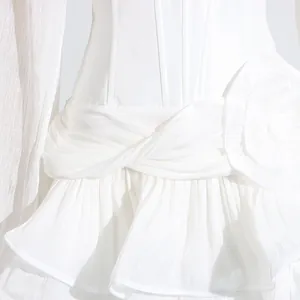 Detailopname witte jurk met 3D-bloem en geplooide ruches detail van de stof