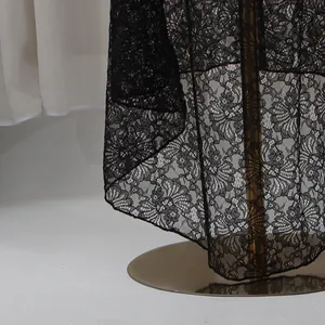 Close-up detail of the intricate black lace floral pattern and hem of an evening gown