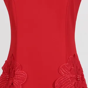 Close-up detail of red sleeveless dress featuring delicate 3D floral appliqués with beads.