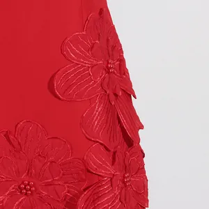 Close-up of elegant 3D floral appliqués with red bead centers on a vibrant dress