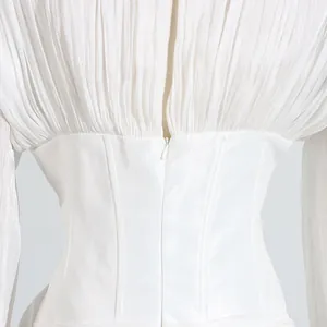Detailopname van een witte jurk in Franse stijl met geplooid lijfje en korset taille.