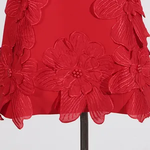 Detailed view of red 3D floral appliqués and beads on a sweet French summer dress