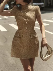 Détail d'une robe courte en tweed doré chic français avec des boutons en perles