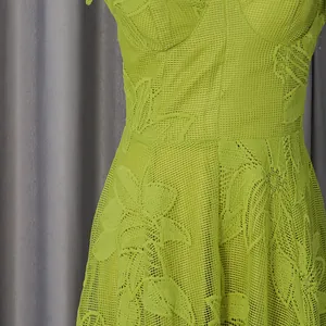 Macro view showing the intricate floral embroidery and mesh texture of this green dress.
