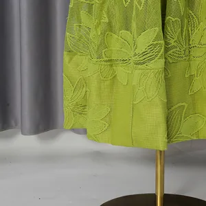 Detailed close-up of lime green floral embroidery lace fabric on a stylish summer maxi dress