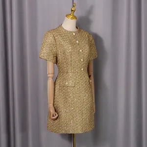 Gros plan d'une mini-robe en tweed doré avec des boutons de perles élégants.