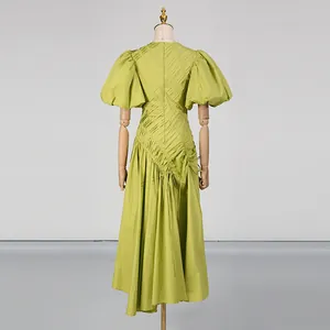 Vista posteriore dettagliata di un abito midi verde a pieghe con eleganti maniche a sbuffo.
