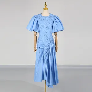 Dettaglio di un abito midi blu a pieghe con maniche a sbuffo e orlo asimmetrico elegante