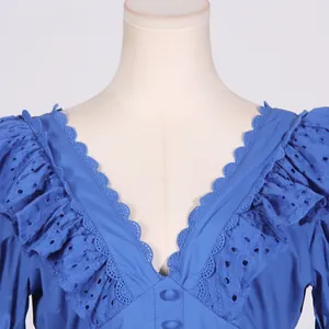 Detail shot of a blue French style dress with V-neckline and ruffled eyelet lace.