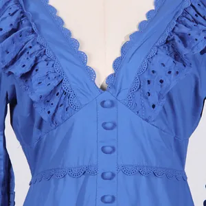 Close-up of V-neckline with broderie anglaise ruffles and buttons on blue dress