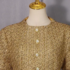 Gros plan d'une robe en tweed doré avec des boutons de perles élégants