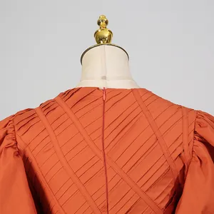 Dettaglio della cerniera invisibile sul retro e del design a pieghe dell'abito arancione