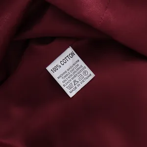 Close-up of 100% cotton care label on wine red luxury cocktail dress.