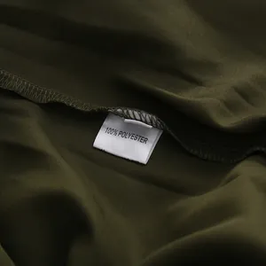 Makro-Detail des 100% Polyester-Etiketts auf einem dunkelolivgrünen Kleidungsstück