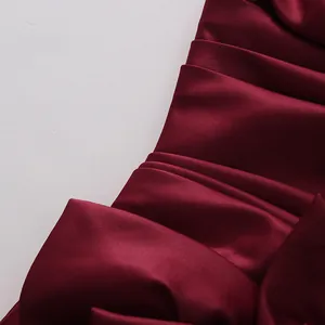 Macro view of luxurious burgundy satin fabric showing elegant pleats and texture