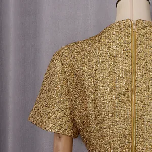 Gros plan sur un tissu en tweed doré luxueux avec paillettes et fermeture éclair au dos