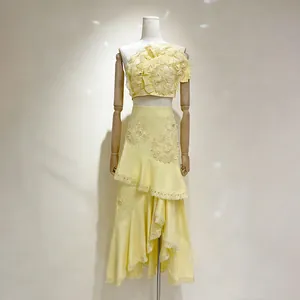 Vue détaillée d'un ensemble jaune deux pièces avec fleurs 3D et volants.