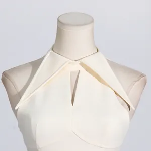 Close-up of white French style sleeveless dress with pointed collar and hollow design